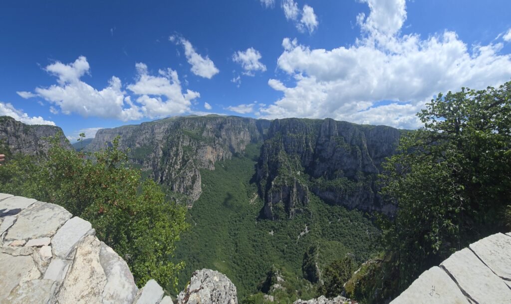 Motorradfahrer genießen Panorama-Ausblick über die Vikos‑Schlucht im Pindos‑Gebirge.