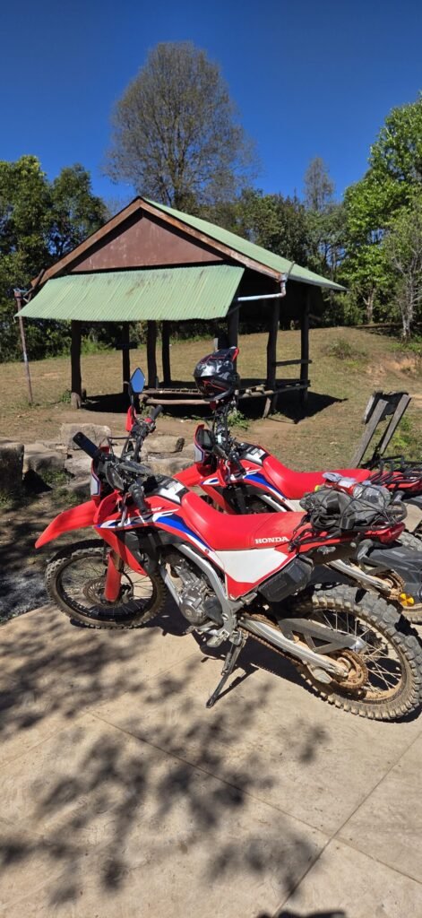 Motorradfahrerin macht Pause auf einer Offroad‑Strecke bei Pai – staubige Kleidung, echtes Abenteuer