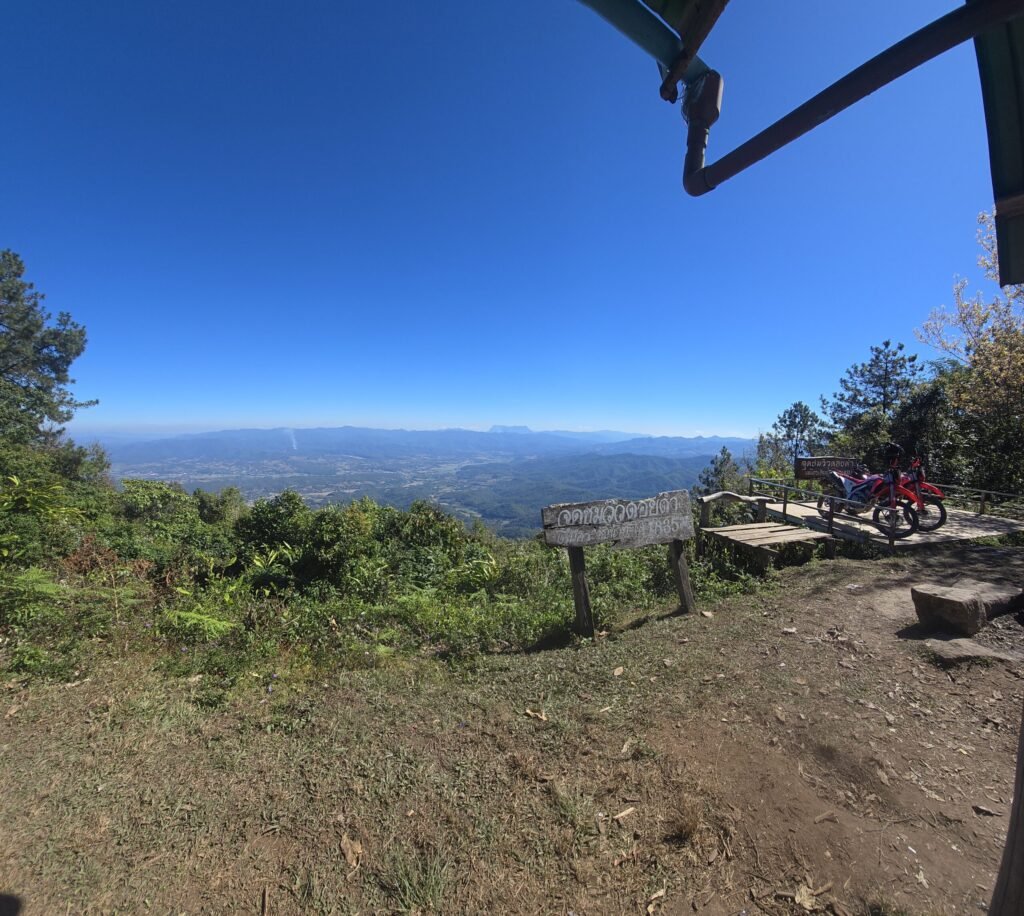 Motorrad auf einer unbefestigten Offroad‑Route nahe Pai – rote Erde und dichter Dschungel