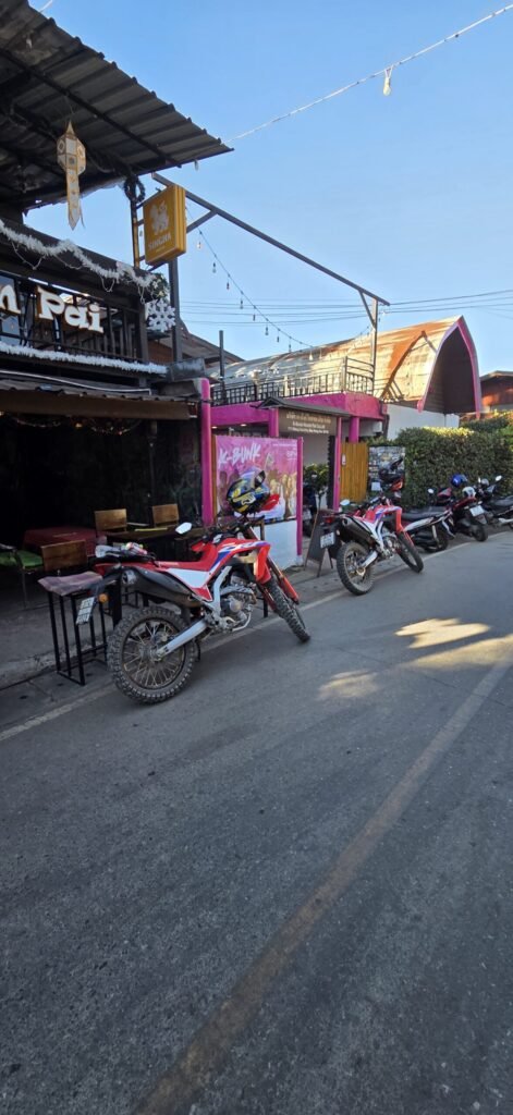 Motorradfahrerin macht Pause auf einer Offroad‑Strecke bei Pai – staubige Kleidung, echtes Abenteuer